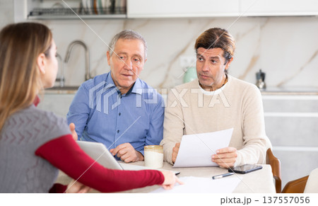 Two men listen attentively to saleswoman talking about the advantages of taking out microloan from credit institution Two men listen attentively to saleswoman talking about the advantages of taking out microloan from credit institution 137557056