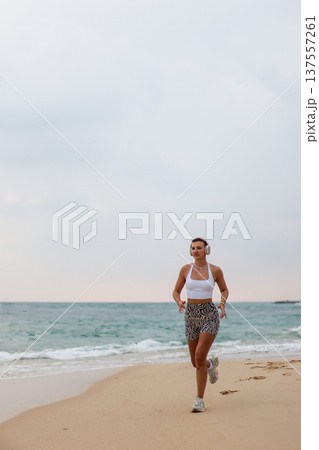 Runner On Beach. Dedicated Athlete Practices Endurance By Jogging Solitary Along Tranquil Ocean Coast 137557261