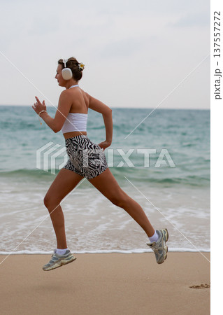 Athletic Woman Running. Active Female Athlete In Stylish Outfit Racing Across Beach During Early Morning 137557272