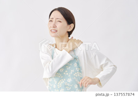 エプロンをつけた女性 肩こり 白背景 エプロンをつけた女性 肩こり 白背景 137557874