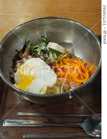 Bibimbap, a vibrant Korean rice dish topped with a variety of seasoned vegetables, gochujang, and a fried egg, often accompanied by sliced meat. Mixed together, it creates a flavorful and balanced. Bibimbap, a vibrant Korean rice dish topped with a variety of seasoned vegetables, gochujang, and a fried egg, often accompanied by sliced meat. Mixed together, it creates a flavorful and balanced. 137559562