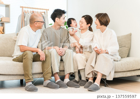 リビングのソファで赤ちゃんを抱っこする母親,三世代家族,ファミリー(初孫,孫) リビングのソファで赤ちゃんを抱っこする母親,三世代家族,ファミリー(初孫,孫) 137559597