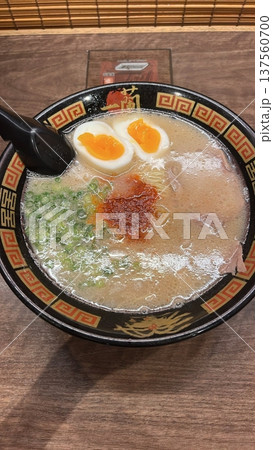 A steaming bowl of ramen with rich broth, tender noodles, sliced pork, boiled egg, nori, and fresh green onions. A comforting and flavorful Japanese classic. 137560700