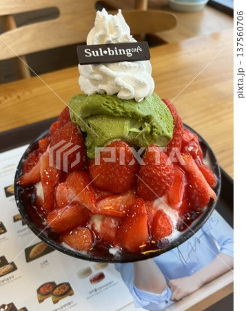 Soft and fluffy strawberry bingsu with finely shaved ice, sweet strawberry syrup, and fresh strawberry slices. A refreshing and delightful Korean dessert, perfect for a cool and fruity treat. 137560706