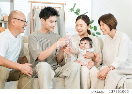 リビングルームでスマホを見ながらくつろぐ三世代家族,ファミリー（団らん） 137561006