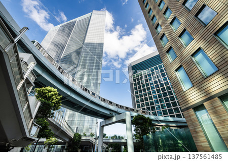 Low-angle view of a New Transit Yurikamome line train running on the elevated track with modern skyscrapers in Shiodome, Minato, Tokyo, Japan. It's an automated guideway transit service in Tokyo. Low-angle view of a New Transit Yurikamome line train running on the elevated track with modern skyscrapers in Shiodome, Minato, Tokyo, Japan. It's an automated guideway transit service in Tokyo. 137561485
