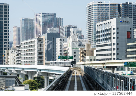 View of a New Transit Yurikamome line train running on the elevated track with modern buildings in Minato, Tokyo, Japan. It's an automated guideway transit service in Tokyo. 137562444