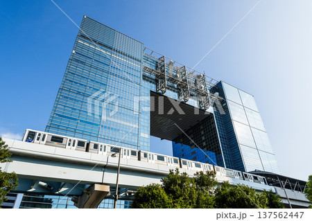 View of a New Transit Yurikamome line train running on the elevated track, driving past the Telecom Center building in Koto, Tokyo, Japan. It's an automated guideway transit service in Tokyo. 137562447
