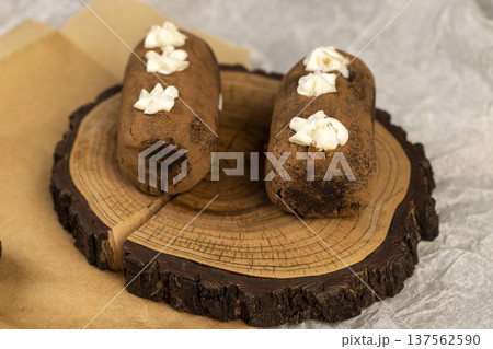 a black potato cake lies on a serving board and paper, a sweet classic cake made from butter and a cocoa mixed with sponge cake and cognac a black potato cake lies on a serving board and paper, a sweet classic cake made from butter and a cocoa mixed with sponge cake and cognac 137562590