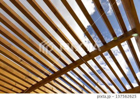 a wooden frame made of logs and planks on the beach against a blue sky with clouds, part of a wooden frame building under construction on the beach to create a good infrastructure a wooden frame made of logs and planks on the beach against a blue sky with clouds, part of a wooden frame building under construction on the beach to create a good infrastructure 137562625