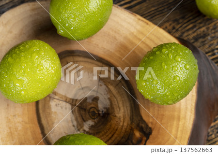wet green ripe citrus limes scattered on the wooden table in the kitchen, ripe lime fruits for cooking, green limes covered with drops of water wet green ripe citrus limes scattered on the wooden table in the kitchen, ripe lime fruits for cooking, green limes covered with drops of water 137562663