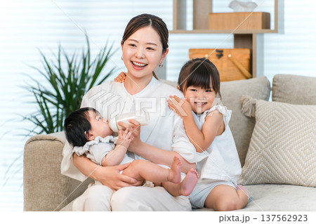 ソファーで赤ちゃんを抱っこする母親,ママ(育児,専業主婦) ソファーで赤ちゃんを抱っこする母親,ママ(育児,専業主婦) 137562923