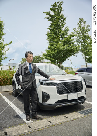 駐車場でSUVに手を置く50代男性ビジネスマン 137562980