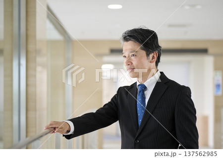 オフィスの廊下で手すりに寄りかかる50代男性ビジネスマン 137562985
