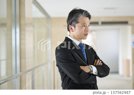 オフィスの廊下で腕を組む50代男性ビジネスマン 137562987