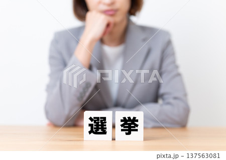 選挙のブロックと悩むスーツ姿のミドル女性 選挙のブロックと悩むスーツ姿のミドル女性 137563081