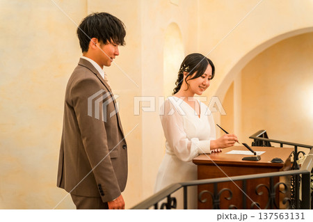 教会で結婚証明書・結婚誓約書にサイン・署名をする新郎新婦 教会で結婚証明書・結婚誓約書にサイン・署名をする新郎新婦 137563131
