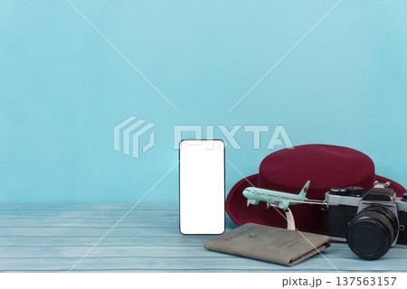 Travel Vibes. Smartphone, camera, and hat on blue background. 137563157