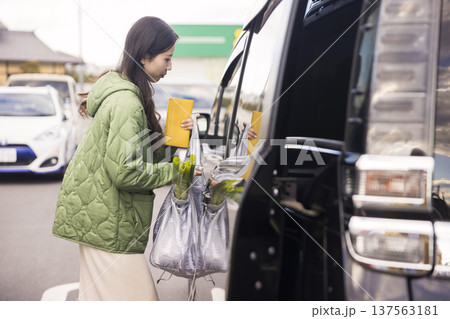 スーパーの駐車場で買ってきた荷物を車に入れる女性 137563181