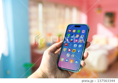 カラフルな部屋でスマートフォンを持つ手 ：はっぴぃぽっぷ 137563344