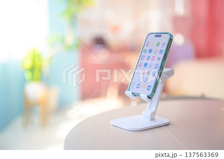 テーブルに置かれたスマホスタンドとスマートフォン ：はっぴぃぽっぷ 137563369