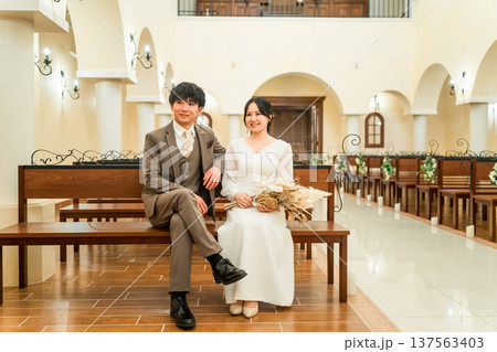 結婚式場,チャペルのベンチに座る新郎新婦（バージンロード・教会・チャペル） 137563403