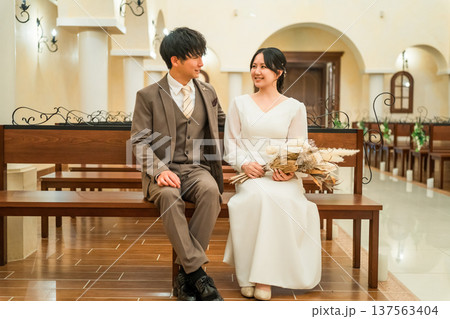 結婚式場,チャペルのベンチに座る新郎新婦(バージンロード・教会・チャペル) 結婚式場,チャペルのベンチに座る新郎新婦(バージンロード・教会・チャペル) 137563404