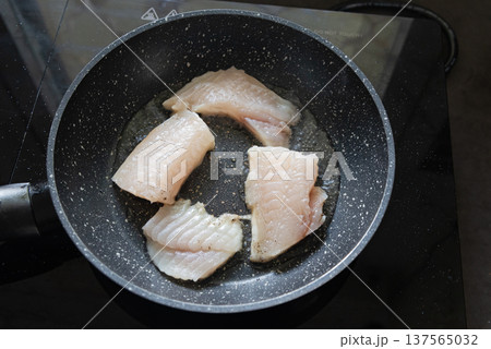 Fish fillet frying in pan on kitchen stove Fish fillet frying in pan on kitchen stove 137565032
