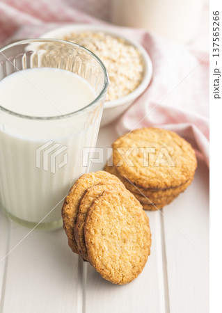 Cookies stacked next to a glass of milk on a wooden table in a bright kitchen setting during daytime Cookies stacked next to a glass of milk on a wooden table in a bright kitchen setting during daytime 137565266