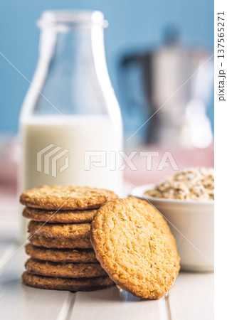 Cookies stacked next to a glass of milk on a wooden table in a bright kitchen setting during daytime 137565271