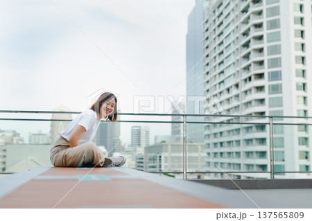 solo asian woman outdoor break and relax with smile and happy feeling at rooftop with city background 137565809