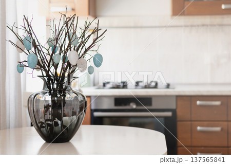Easter decoration with branches and eggs in vase on kitchen table Easter decoration with branches and eggs in vase on kitchen table 137565841