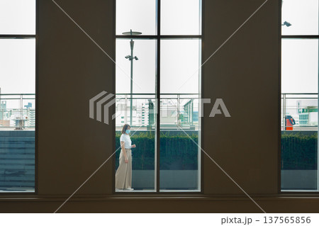 solo asian woman wear protective mask during outdoor break and relax at rooftop with city background 137565856