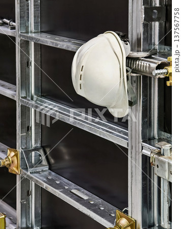 Construction site shows a safety helmet hanging on metal framework during work hours in a building project in the city Construction site shows a safety helmet hanging on metal framework during work hours in a building project in the city 137567758