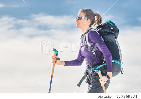 Female ski mountaineer hiking with touring skis in alpine mountains 137569531