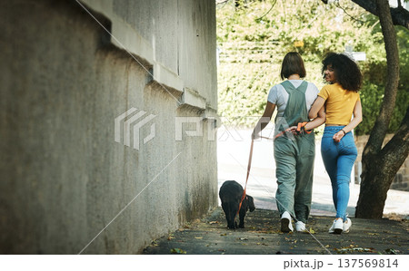 Women, walking and couple with a dog in street, park or portrait outdoor in spring with pet on lead and wall mockup space. People, smile and journey with animal for exercise, wellness or happiness 137569814
