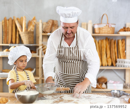 Bakers dad teaches daughter niece to work with dough, using rolling pin Bakers dad teaches daughter niece to work with dough, using rolling pin 137569952