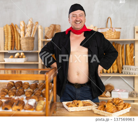 Obese male salesman stands near glass display case and table in bakerys sales area 137569963