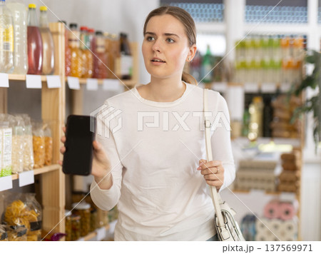 Young woman buyer shows information on phone screen 137569971