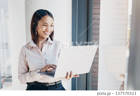 Happy woman at office window, with laptop and reading email research, schedule or online for feedback. Internet, networking or communication on website, businesswoman smile at human resources agency 137570321