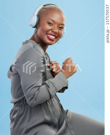 Portrait, dance and happy black woman with music headphones in studio for audio streaming on blue background. Radio, face and African female model smile for podcast earphones, track or playlist 137570537