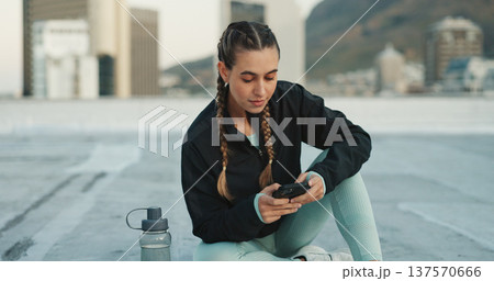Phone, exercise and woman on social media in city on a rooftop on workout break outdoor. Fitness, communication and girl athlete networking on the internet with smartphone after cardio training 137570666
