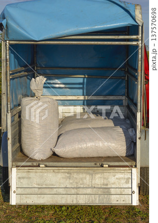 White Sacks Loaded in Small Trailer with Blue Tarp White Sacks Loaded in Small Trailer with Blue Tarp 137570698