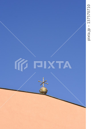 Golden Metal Cross Ornament on Building Roof Against Blue Sky 137570710