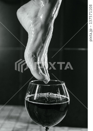 Foot fetish. A woman dips her toes in a glass of red wine. Foot fetish. A woman dips her toes in a glass of red wine. 137571108