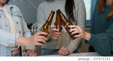Cheers with Beer Bottles. Friends toasting with beer bottles in a modern kitchen. Cheers with Beer Bottles. Friends toasting with beer bottles in a modern kitchen. 137571131