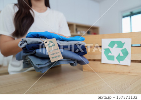 Sustainability. Woman organizing clothes made from recycled materials in eco-friendly lifestyle. Sustainability. Woman organizing clothes made from recycled materials in eco-friendly lifestyle. 137571132