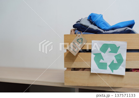 Sustainability. Wooden box with recycled clothes promoting eco-friendly practices. Sustainability. Wooden box with recycled clothes promoting eco-friendly practices. 137571133