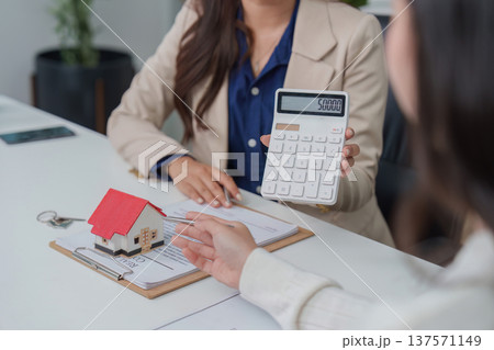 Real Estate Consultation. Financial advisor discussing home purchase with client using calculator. 137571149