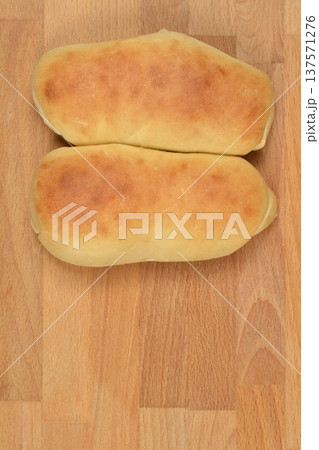 Two freshly baked long rolls on a wooden background Two freshly baked long rolls on a wooden background 137571276
